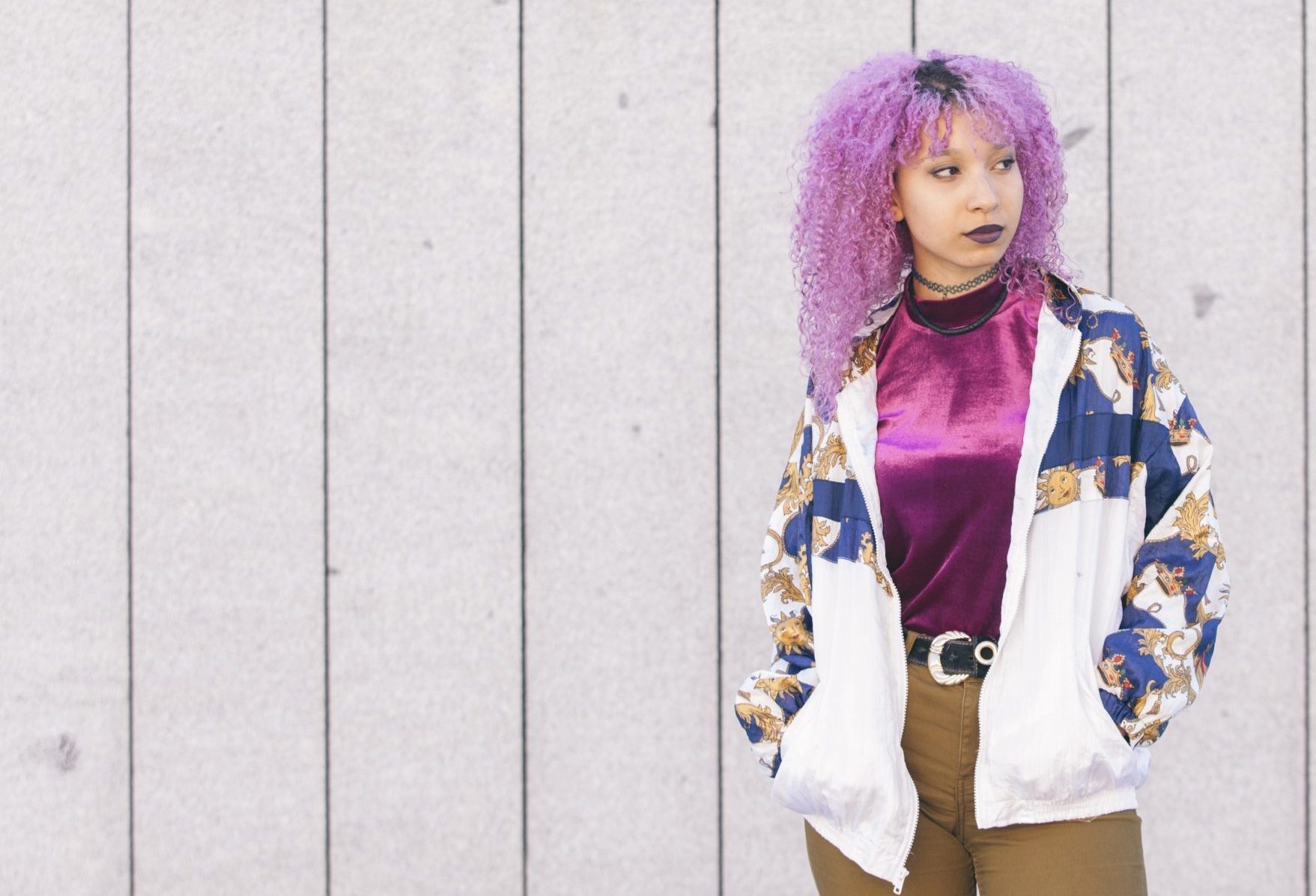 racially ambiguous woman with purple hair looking into the distance